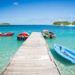 Caribbean Island - three boats are docked at the end of a pier