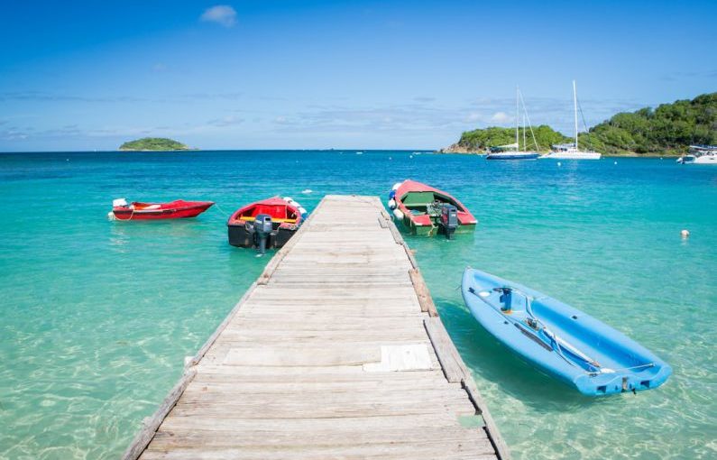 Caribbean Island - three boats are docked at the end of a pier