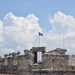 Cuban Flag - a flag flying on top of a stone wall