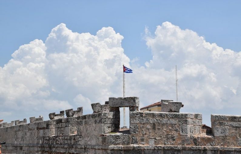 Cuban Flag - a flag flying on top of a stone wall