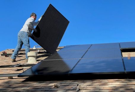 Solar Panels - man in white dress shirt and blue denim jeans sitting on white and black solar panel