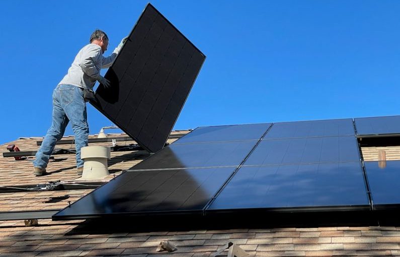 Solar Panels - man in white dress shirt and blue denim jeans sitting on white and black solar panel