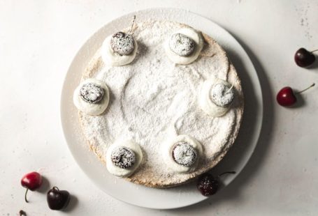 Powdered Sugar - white and black round cake with black berries on white ceramic plate