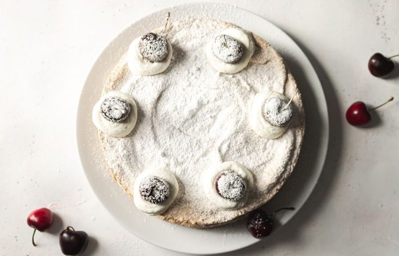 Powdered Sugar - white and black round cake with black berries on white ceramic plate