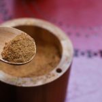 Coconut Sugar - brown wooden round container on pink textile