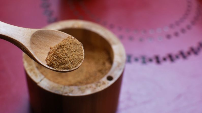 Coconut Sugar - brown wooden round container on pink textile