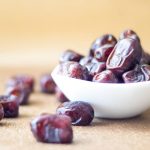 Dates - brown round fruit on white ceramic bowl