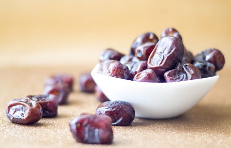 Dates - brown round fruit on white ceramic bowl