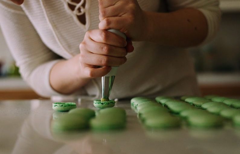 Pastry Chef - selective focus photography of woman putting icing on cupcakes