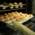 Baking Oven - person holds tray of muffins on tray