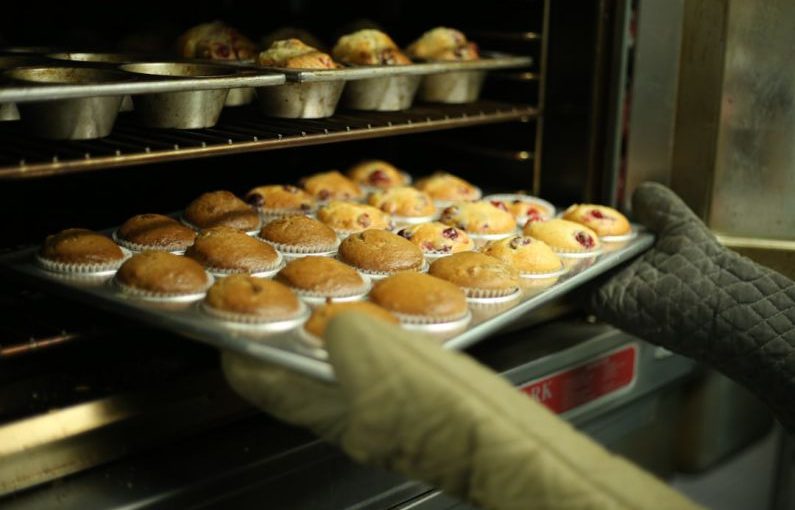 Baking Oven - person holds tray of muffins on tray